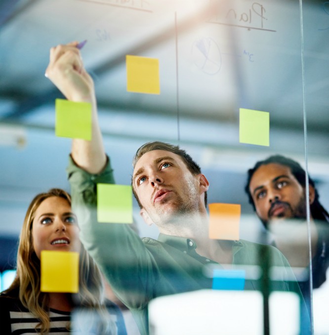 Team members working together as seen through a glass wall.