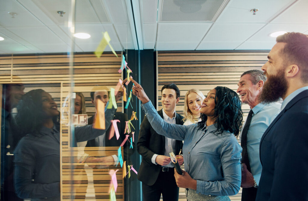 Smiling multiethnic staff at the wall with stickers on a meeting in the company.