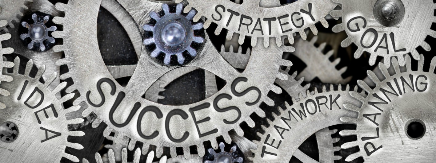 Industrial gears etched with inspirational words including idea, planning, success, teamwork, strategy, vision, and goals.